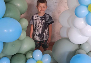 Emil pozuje wśród dekoracji z balonów