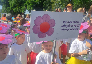 Dziewczynka trzyma w ręku transparent z nazwą przedszkola