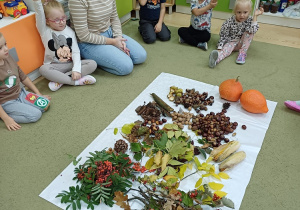 Dzieci wraz z nauczycielem siedzą na dywanie