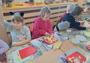 Dzieci przy stoliczkach kroją owoce i warzywa do koktajlu