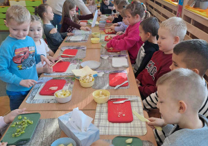 Dzieci przy stoliczkach kroją owoce i warzywa do koktajlu