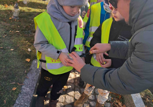 Dzieci zapalają znicze z pomocą nauczycielki