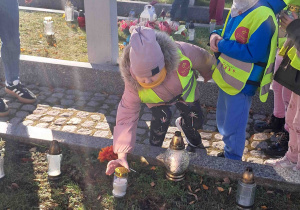 Dzieci ustawiają znicze przy grobach żołnierzy