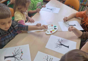 Dzieci malują kolorowe liście używając patyczków higienicznego.