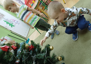 Dzieci ubierają choinkę w sali przedszkolnej