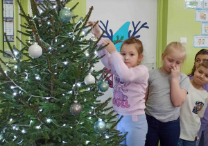 Dzieci ubierają choinkę.