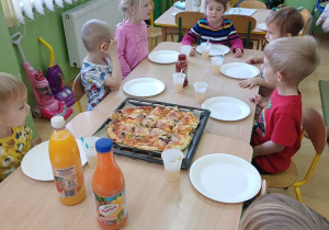 Dzieci siedzą przy stolikach i czekają na pizzę