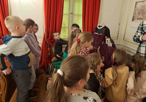 Dzieci zwiedzają muzeum i oglądają stroje dam dworu