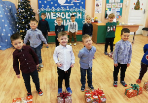 Chłopcy stoją za prezentami położonymi na podłodze