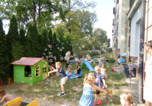 Dzieci bawią się na placu zabaw w przedszkolnym ogródku.