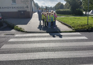 Dzieci przechodzą przez pasy pod czujnym okiem nauczyciela