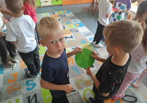 Dzieci bawią się przy muzyce na dywanie.. W przerwie dobierają się w pary z taką samą kropką.