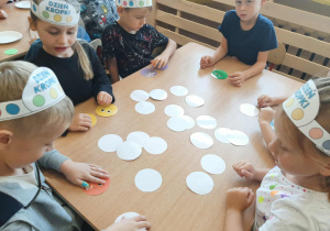 Dzieci siedzą przy stoliku i grają w memory. Dobierają dwie takie same kropki.