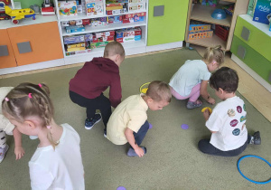 dzieci na dywanie segregują kropki wg koloru