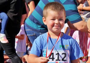 Chłopiec w niebieskiej koszulce prezentuje medal