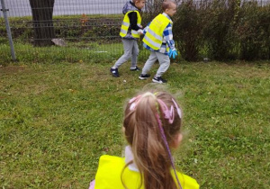 Dzieci spacerują i zbierają śmieci do worka