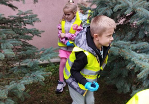 Dzieci spacerują i zbierają śmieci do worka