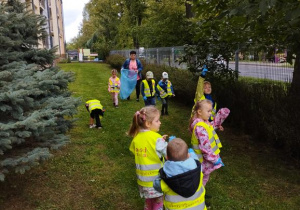 Dzieci spacerują i zbierają śmieci do worka