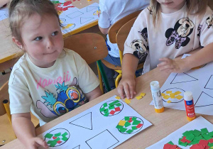 Dzieci wyklejają kontur koła przy stoliku