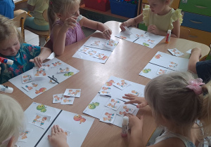 dzieci wykonują karte pracy przy stoliku