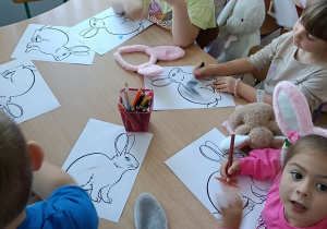 Dzieci kolorują obrazek z królikiem.