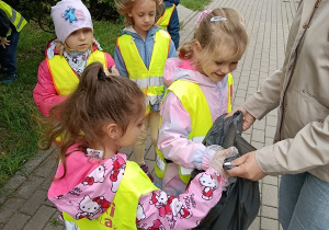 Dziewczynki wyrzucają odpadki do worka.
