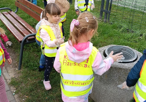 Dzieci wyrzucają śmieci do kosza.