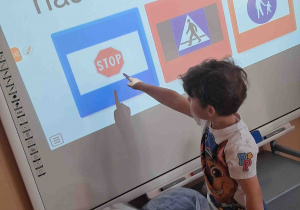 Dzieci zaznaczają na tablicy multimedialnej odpowiedzi dotyczące ruchu drogowego