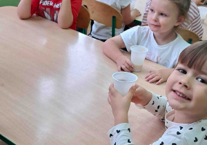 Dzieci przy stolikach piją samodzielnie zrobiony sok z jabłek