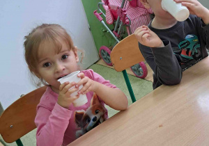 Dzieci przy stolikach piją samodzielnie zrobiony sok z jabłek