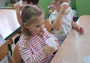 Dzieci przy stolikach piją samodzielnie zrobiony sok z jabłek