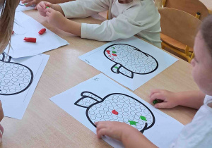 Dzieci przy stoliku wylepiają plasteliną kontur jabłka