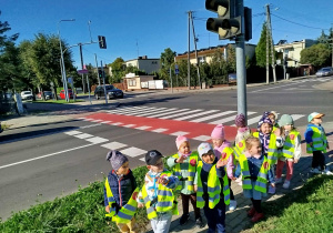 Dzieci pozują do zdjęcia na tle skrzyżowania.