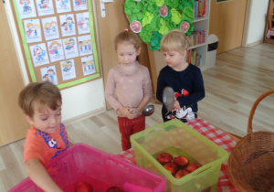 Dzieci pozują do zdjęcia przy łowieniu jabłek.