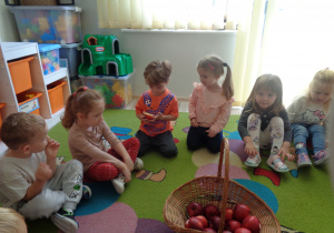Dzieci uczestniczą w zabawie na dywanie.