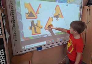 Dzieci układają kształty znaków drogowych na tablicy multimedialnej