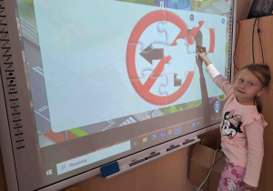 Dzieci układają kształty znaków drogowych na tablicy multimedialnej