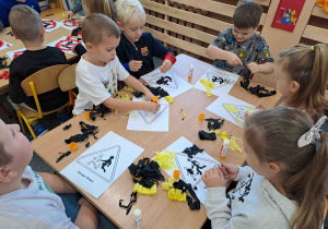 Dzieci wykonują pracę plastyczną - znaki drogowe techniką wyklejanki