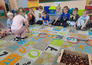 Dzieci tworzą zbiory o wskazanej liczbie elementów umieszczając kasztany w obręczach
