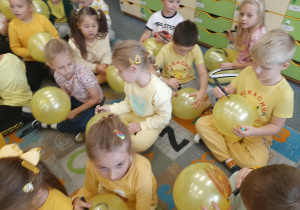 Dzieci malują na balonie mazakiem buźki uśmiechnięte.