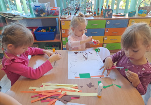 Dzieci wykonują prace w grupach przy stoliku