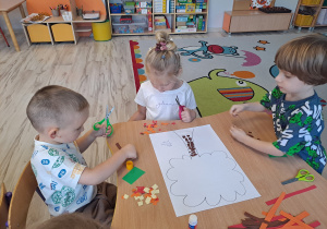 Dzieci wykonują prace w grupach przy stoliku