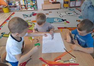 Dzieci wykonują prace w grupach przy stoliku