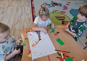 Dzieci wykonują prace w grupach przy stoliku