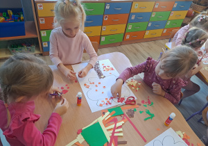 Dzieci wykonują prace w grupach przy stoliku