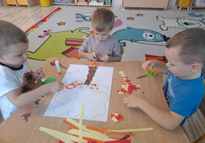 Dzieci wykonują prace w grupach przy stoliku
