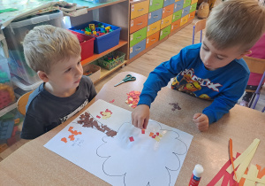 Dzieci wykonują prace w grupach przy stoliku