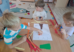 Dzieci wykonują prace w grupach przy stoliku