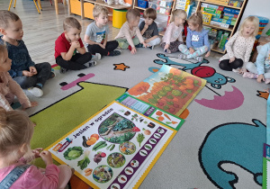 dzieci siedza na dywanie, na środku ilustracje sadu i ogrodu