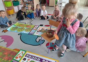 dzieci siedza na dywanie, na środku ilustracje sadu i ogrodu